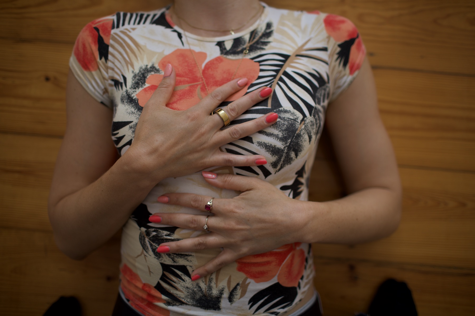 Overhead view of hands crossed gently over the chest, a small gesture of self-soothing